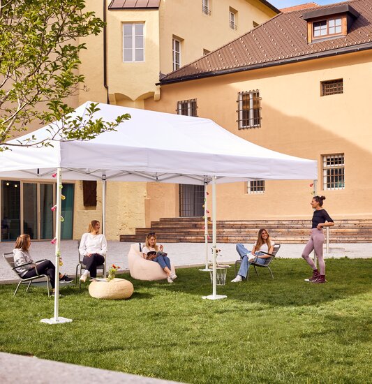 Der 6x3 m große Faltpavillon dient als Outdoor-Überdachung einer Bibliothek. Darunter sitzen Jugendliche.