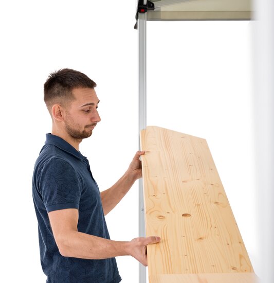 Uomo che monta un bancone in legno su un gazebo pieghevole Ecotent  per parete laterale a mezza altezza.