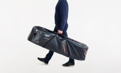 The man carries the black side wall bag. The folding gazebo side walls are in there.