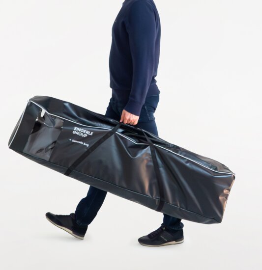 The man carries the black side wall bag. The folding gazebo side walls are in there.