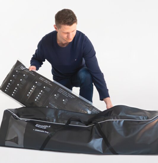 The man packs the folding gazebo side walls in the black side wall bag.